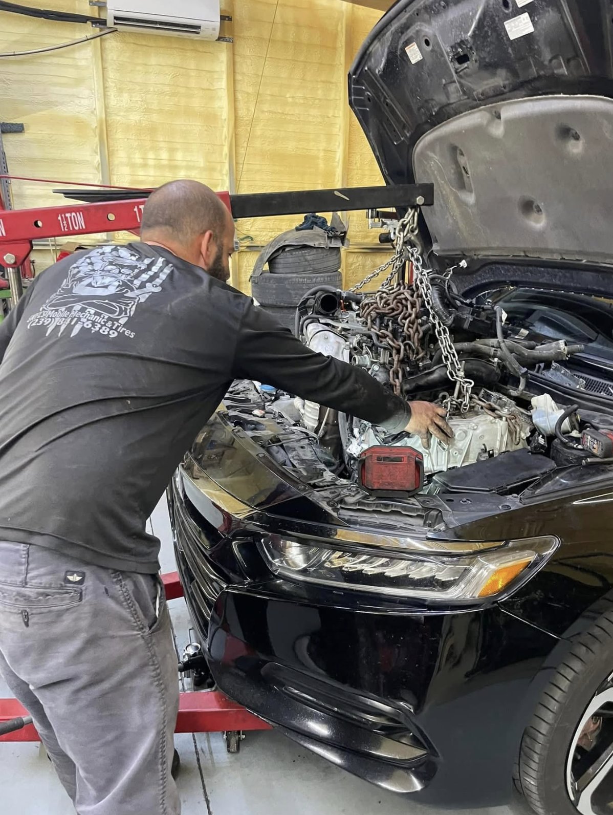 Mechanic working on an engine swap with a chain hoist