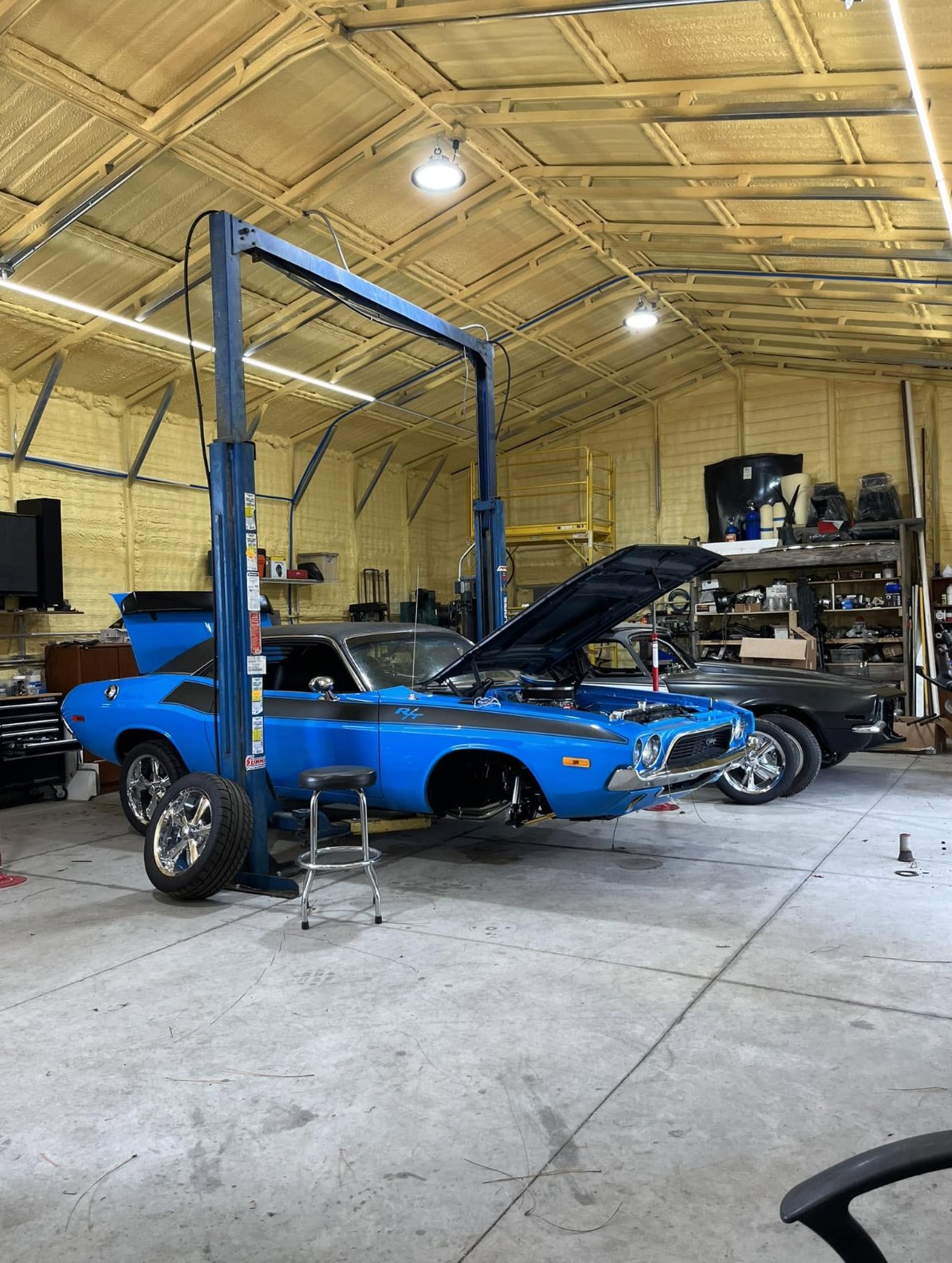 Classic muscle car up on the two-post lift inside the shop
